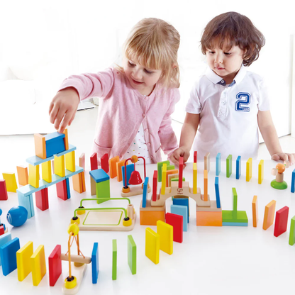Children intently build a chain reaction structure using colorful wooden dominoes