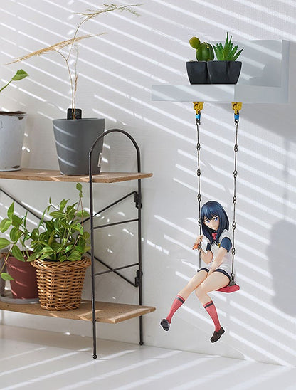 Anime schoolgirl figure on a tiny red swing hanging from a white shelf with miniature potted plants