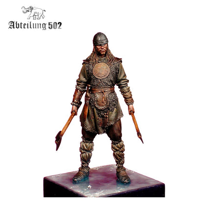 A hand-painted miniature of a Viking warrior in a helmet and fur, holding two axes, standing on a base