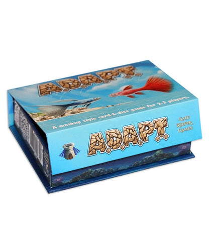 Slightly open 'ADAPT' board game box. Artwork shows blue and red fish above a sandy horizon. Stone-textured 'ADAPT' title.