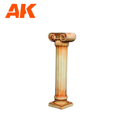 Orange AK Interactive logo above a light brown Ionic column with a square base on a white background