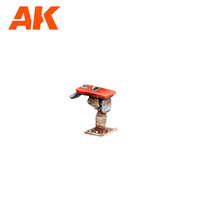 A weathered miniature red and metal device on a rusty base, AK Interactive logo