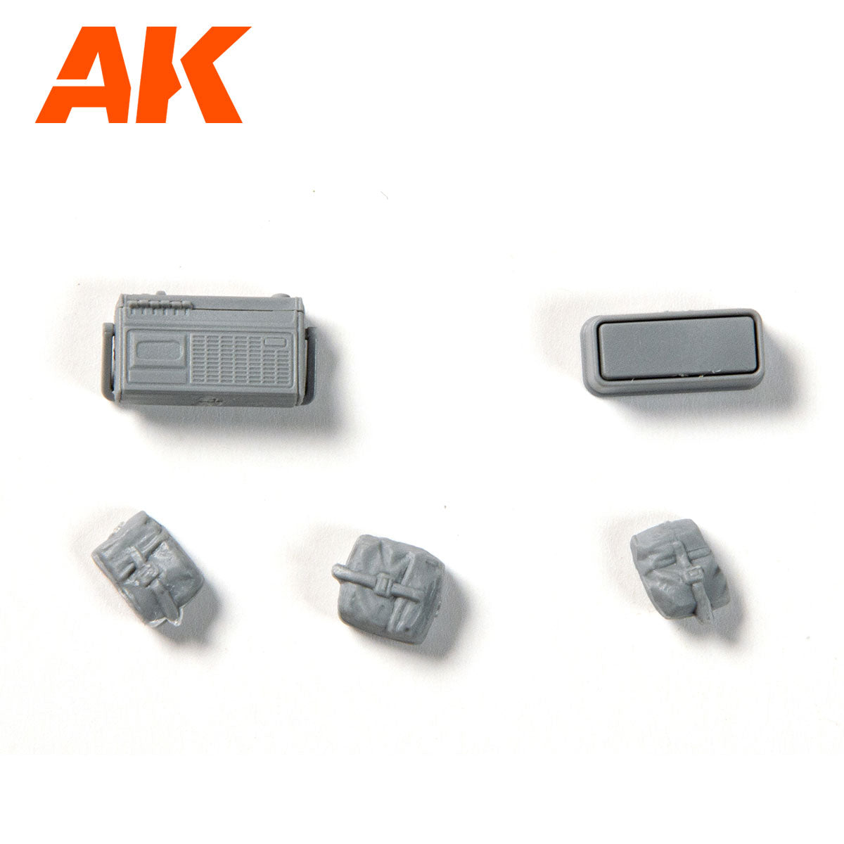 AK model accessories: A gray miniature radio -  a rectangular box -  and three rolled tarps on a white background