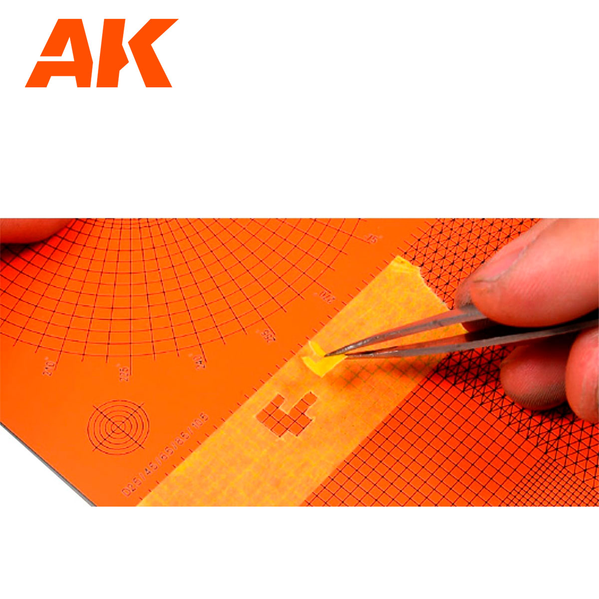 AK logo. A hand uses tweezers to precisely place a small yellow masking tape detail onto an orange grid crafting mat