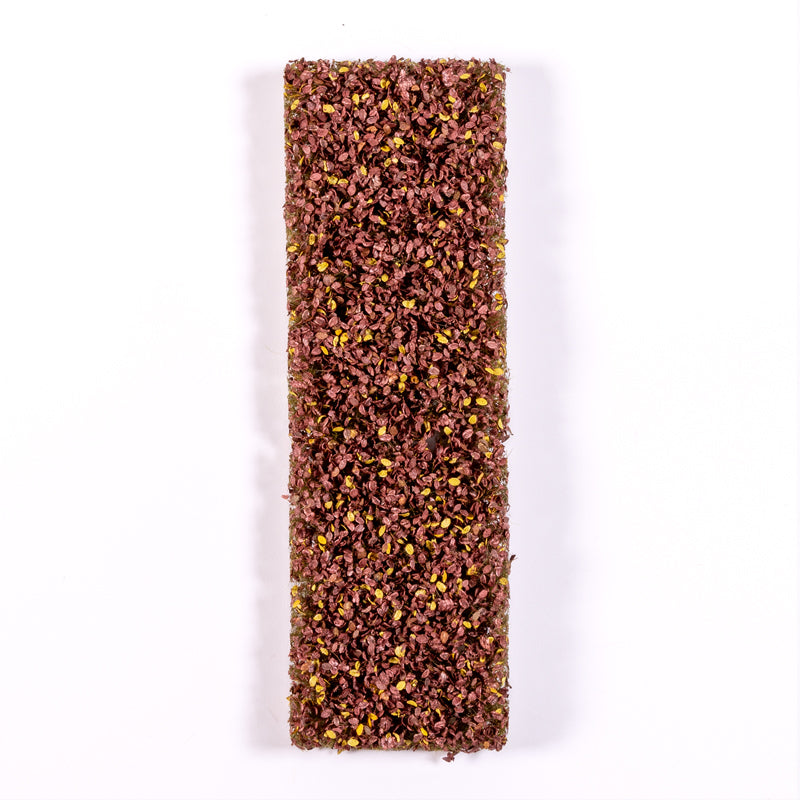 A vertical rectangular block densely covered with tiny maroon and yellow artificial foliage