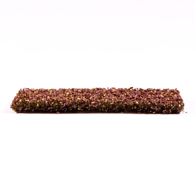 A rectangular mat of model ground cover with dense reddish-brown and yellow flakes
