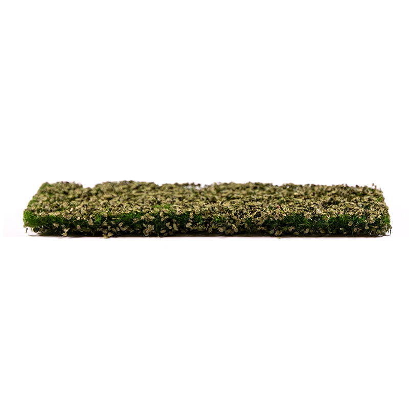 Thick, rectangular artificial foliage mat, densely textured with mixed green and brown leaves, on white