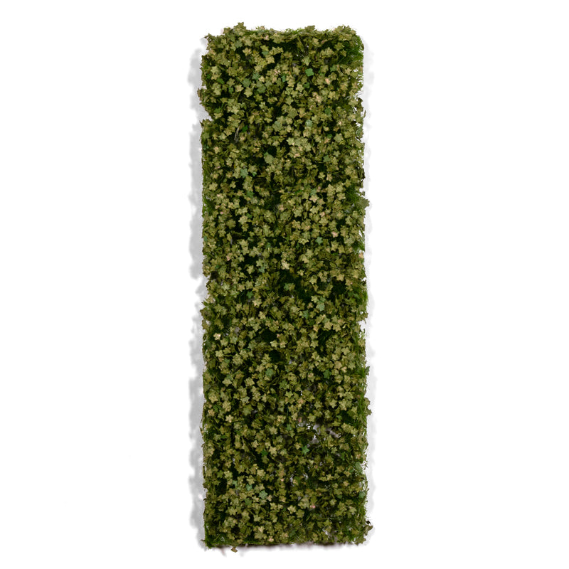 A rectangular panel densely covered in small green artificial leaves, casting a shadow on a white background
