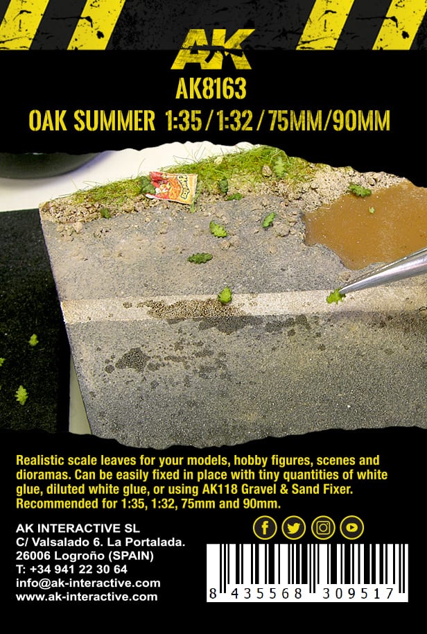 Tweezers carefully place a tiny green scale leaf onto a miniature diorama base, showing a dirt road, grass, and a puddle