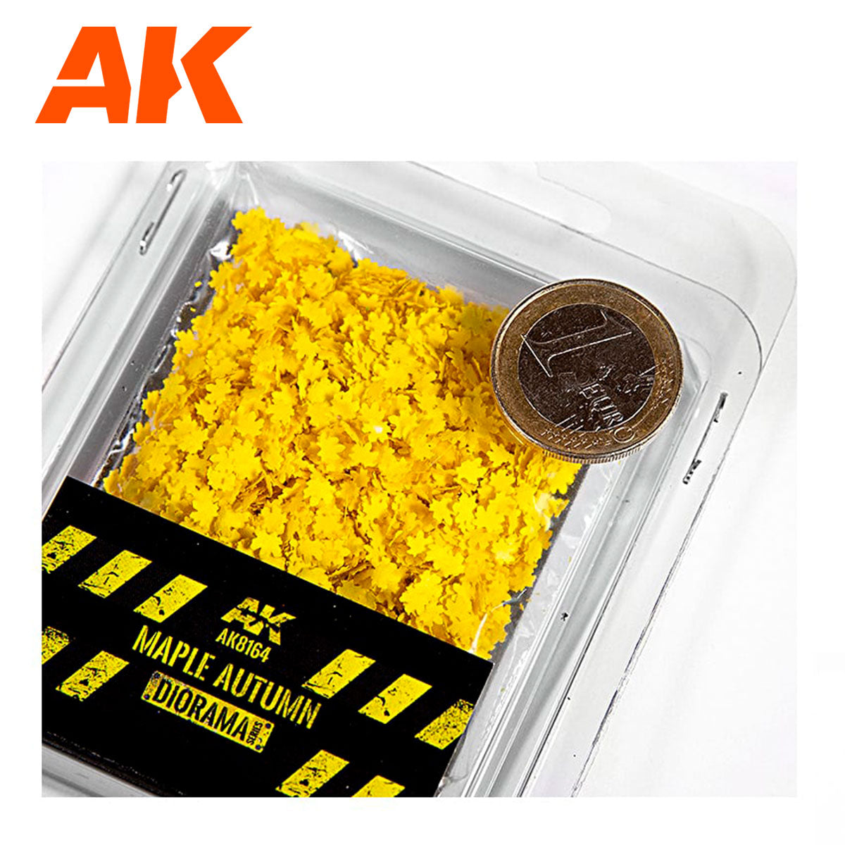A clear container of tiny bright yellow maple autumn leaves for dioramas, with a 1 Euro coin for scale