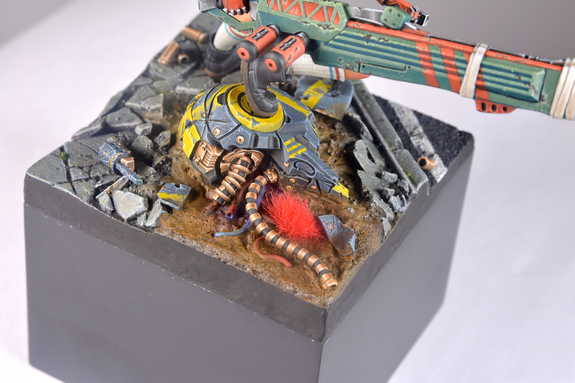 A detailed miniature diorama features AK Interactive Vegetation Red Wargame Tufts 4mm as bright red foliage on a muddy ground base with a sci-fi foot and debris