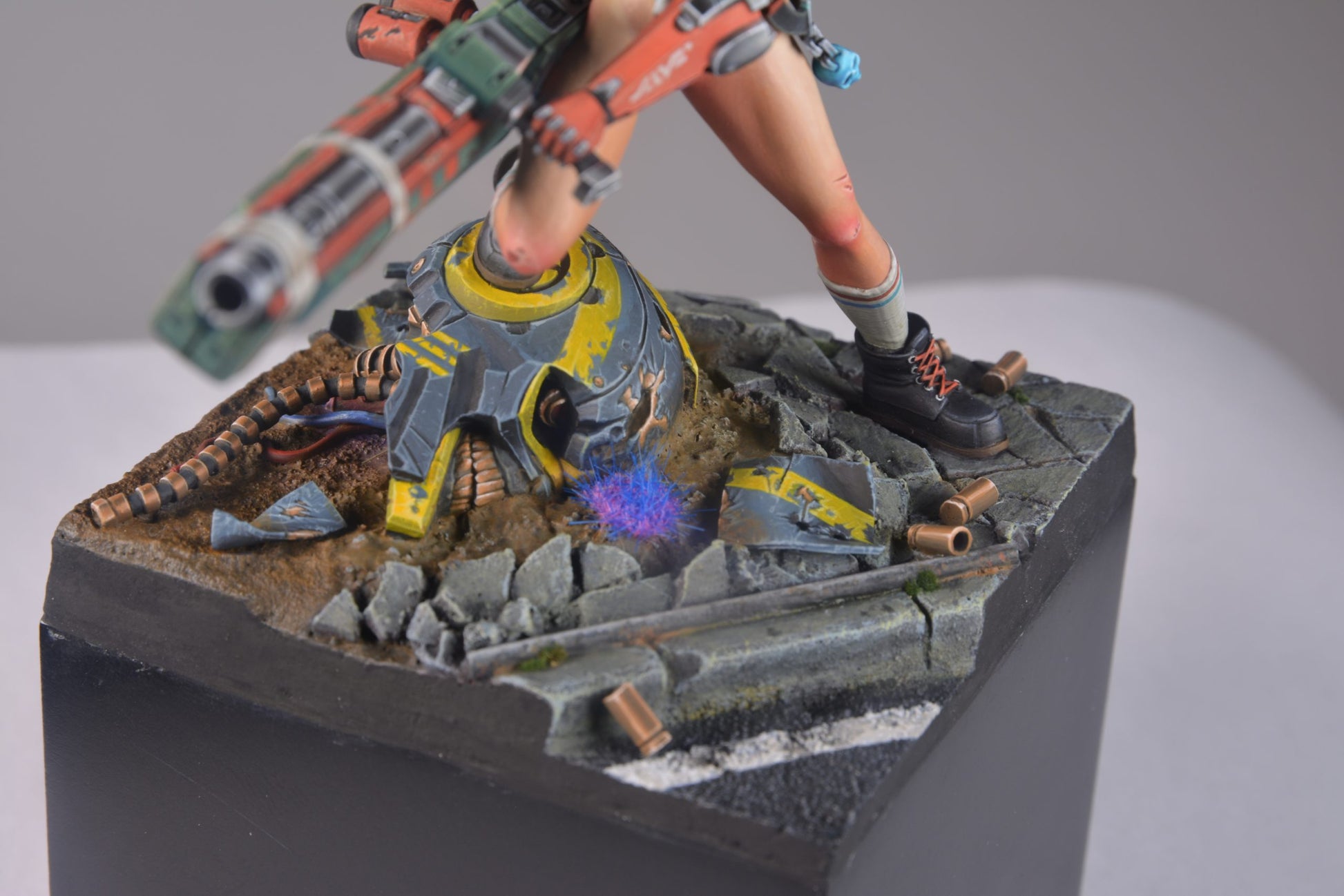 A sci-fi figure stands over a glowing -  broken robot helmet on a rubble-strewn road -  holding a large weapon