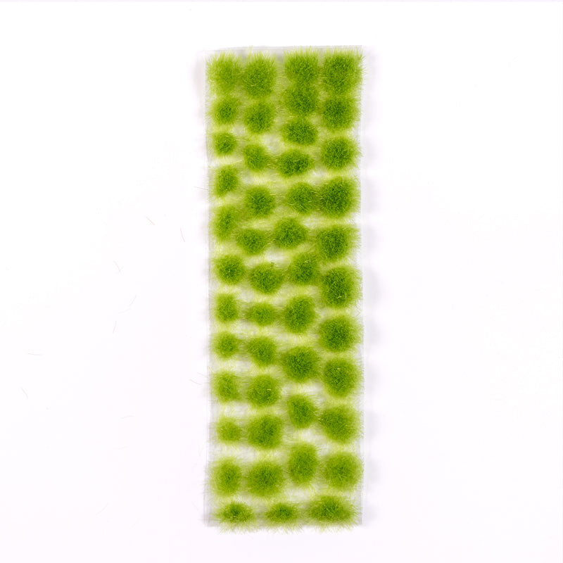 AK Interactive Vegetation Light Green Tufts 4mm are presented as numerous fuzzy, circular light green clusters arranged on a clear rectangular strip against a white background