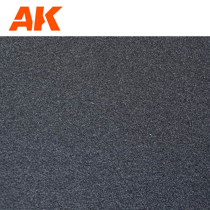 Close-up of a coarse, dark gray textured surface sandpaper with an orange "AK Interactive " logo in the top left