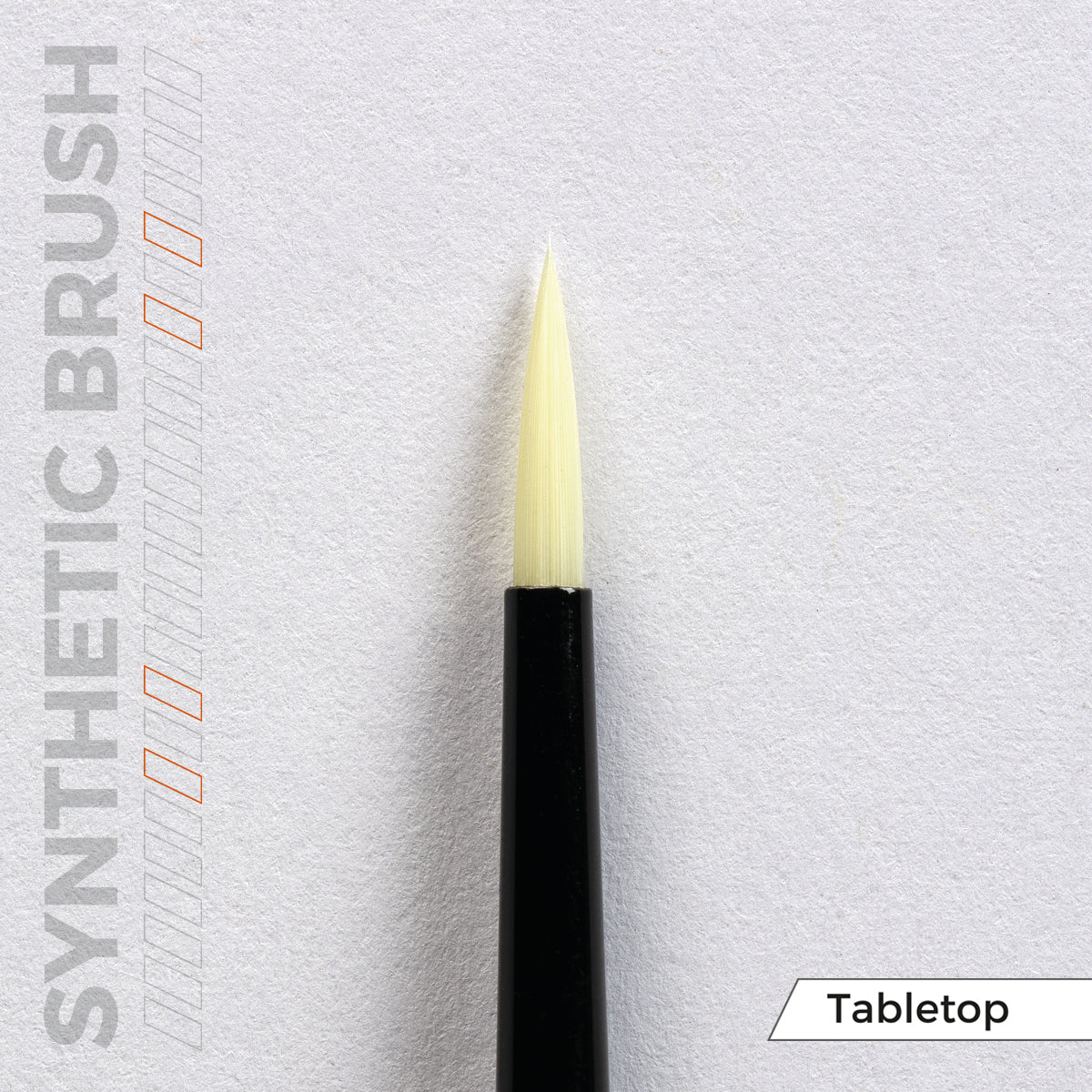 A synthetic brush with a black handle and pointed cream bristles, on a white tabletop background