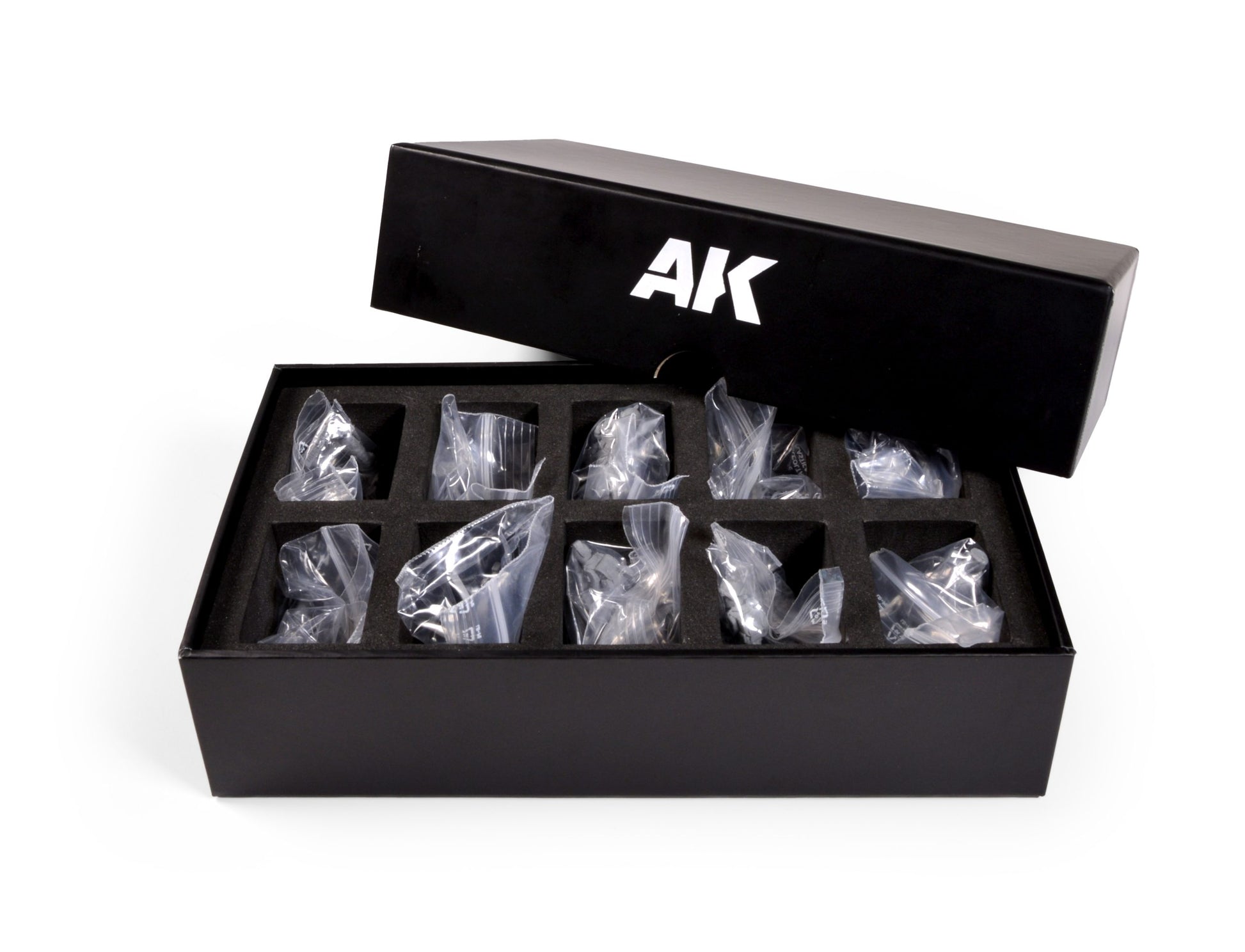 Open black box with AK logo containing small, bagged items in a foam insert