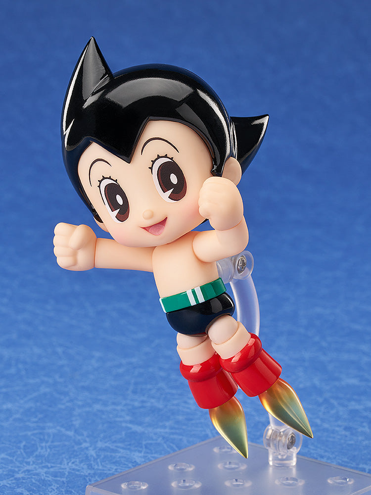 A smiling Astro Boy figure in blue shorts and rocket boots flying upwards against a blue background
