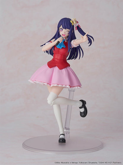 A vibrant anime idol figure with purple hair, winking and holding a mic. She wears a red top, pink skirt, and points excitedly