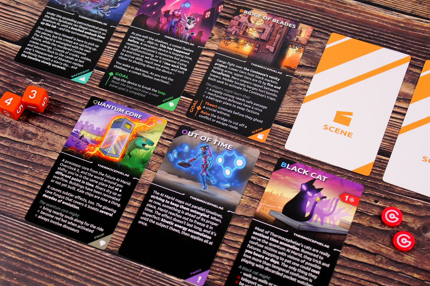 Various colorful cards featuring artwork from the Thermocephalae tabletop game laid out on a wooden surface next to orange dice and red tokens