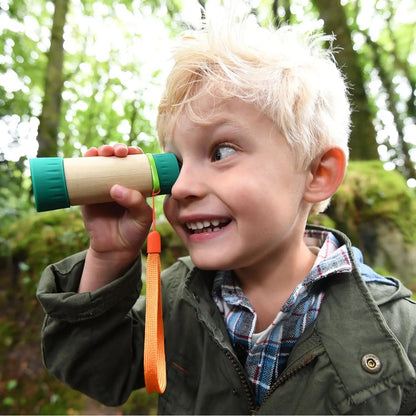 Excited child looking through a small bamboo telescope in a forest
