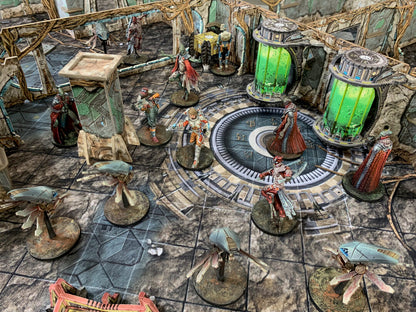 Tabletop sci-fi game with painted miniatures: characters, drones, and robed figures on a ruined map with glowing green tanks