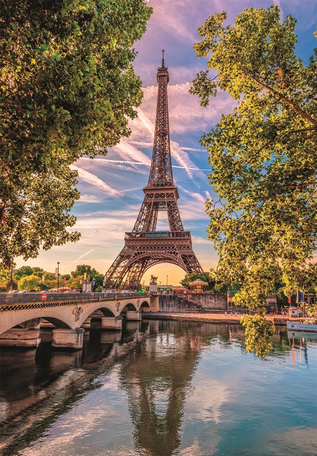 The Eiffel Tower rises above a bridge on the Seine River, framed by trees, its reflection visible in the water at dusk.