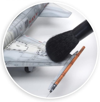 A soft brush detailing a gray model Navy jet wing. A metal scribing tool is visible.
