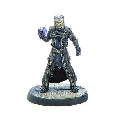 A fantasy elf wizard miniature with pale skin and white hair, wearing dark robes, holding a glowing purple crystal