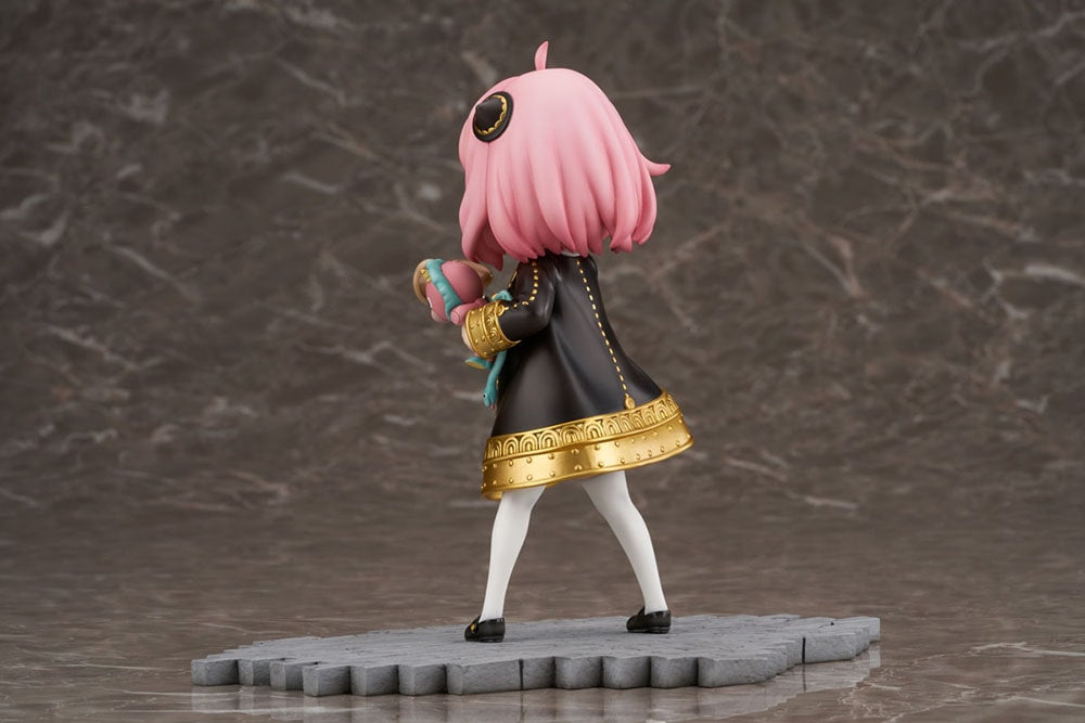 Backside view of Anya Forger figure in a black dress, holding a megaphone and a pink Chimera plush