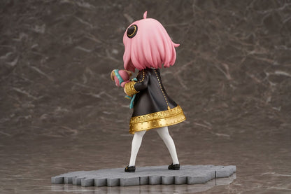 Backside view of Anya Forger figure in a black dress, holding a megaphone and a pink Chimera plush