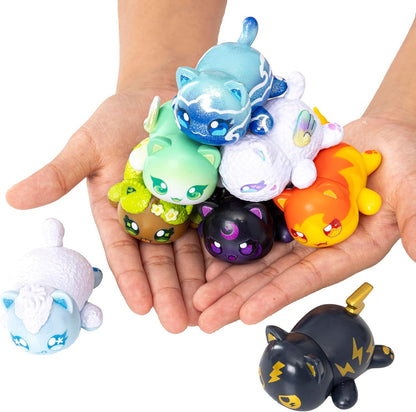 A person's hands hold a pile of diverse, colorful cat toy figures, with two more nearby on a white surface