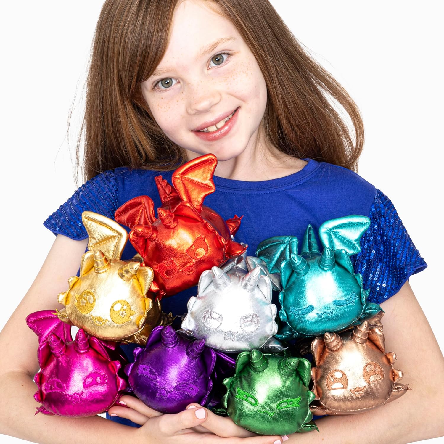 Smiling girl holds a pile of shiny, colorful dragon plush toys in her arms