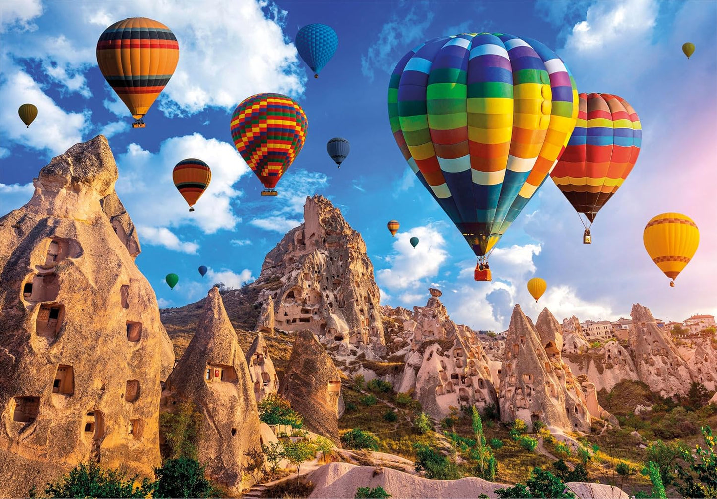 Many colorful hot air balloons soar above unique fairy chimney rock formations and cave dwellings of Cappadocia.