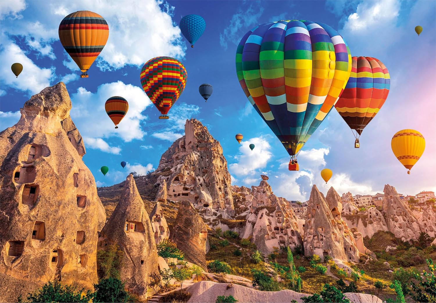 Many colorful hot air balloons soar above unique fairy chimney rock formations and cave dwellings of Cappadocia.