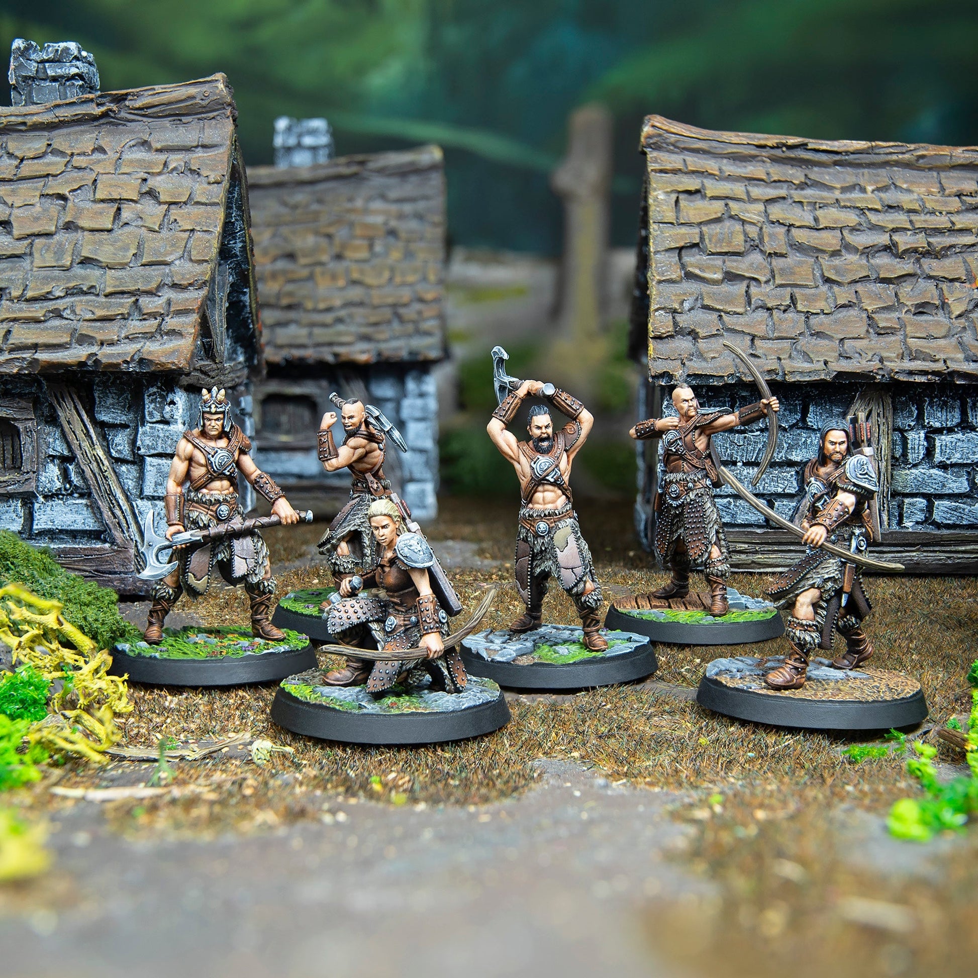 Six fantasy warrior miniatures with axes and bows in a detailed village setting
