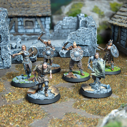 Six painted fantasy miniatures, wielding axes and shields, on a detailed battlefield diorama with stone ruins