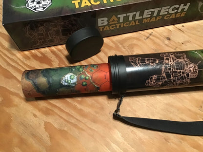 A black BattleTech map case with mech art, partially unrolled to reveal a colorful hex-grid terrain map. Its lid is nearby