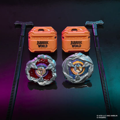 Two metallic Beyblade X Jurassic World spinning tops, orange storage cases and black launchers displayed on a dark surface