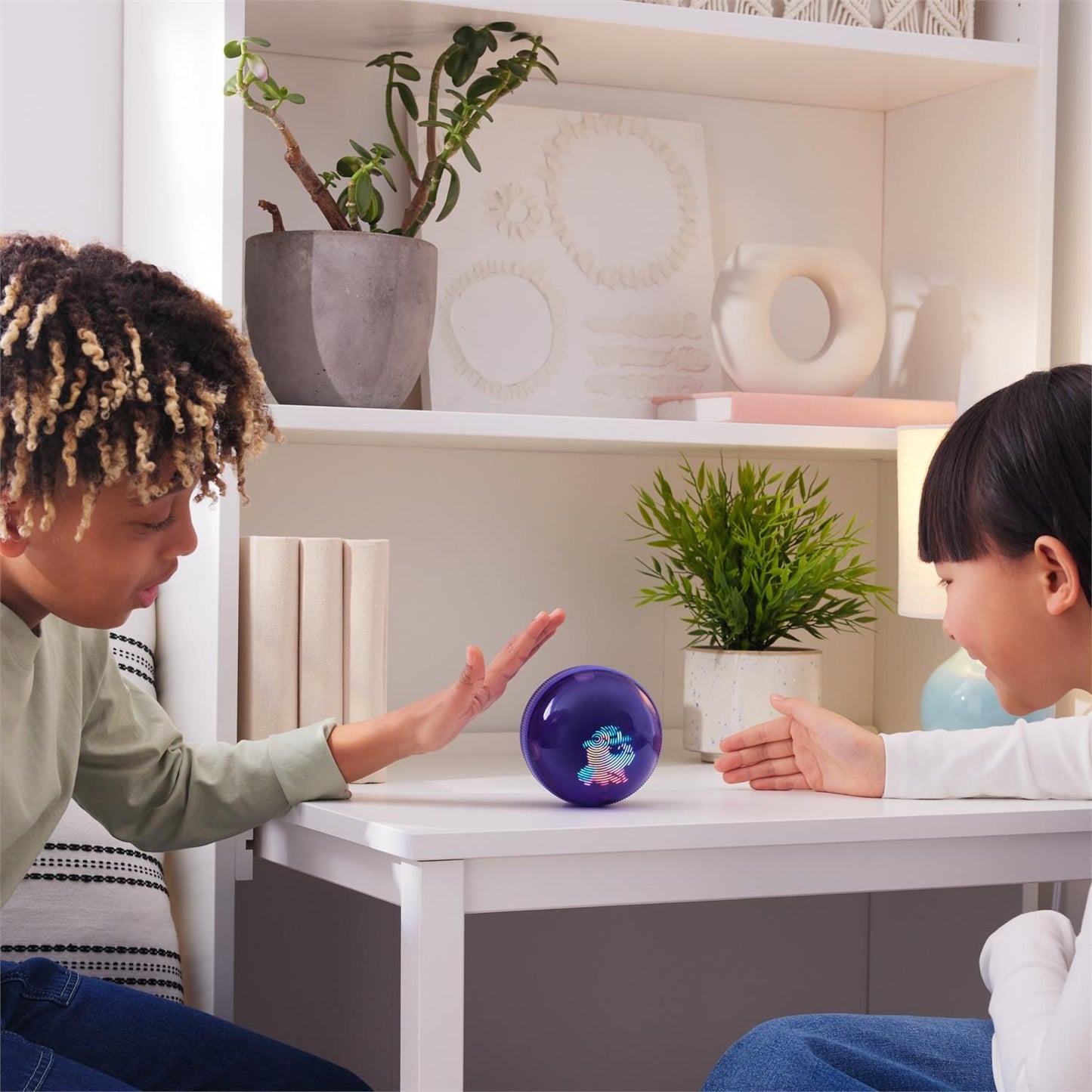 Two children playing with a glowing purple ball showing a colorful fingerprint on a white table