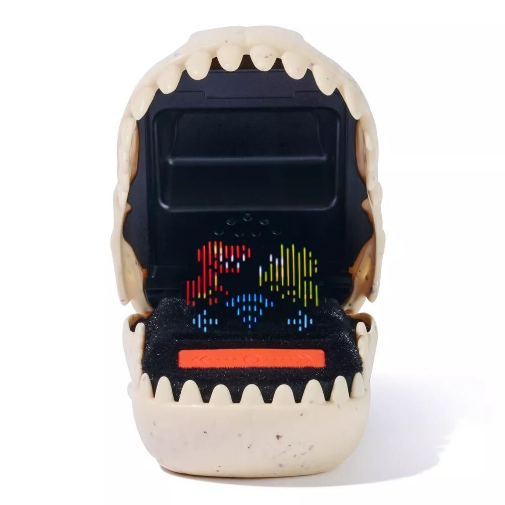 Bone-colored dinosaur skull-shaped handheld game, mouth open revealing a pixelated screen with red and blue dinosaur figures, orange control button visible