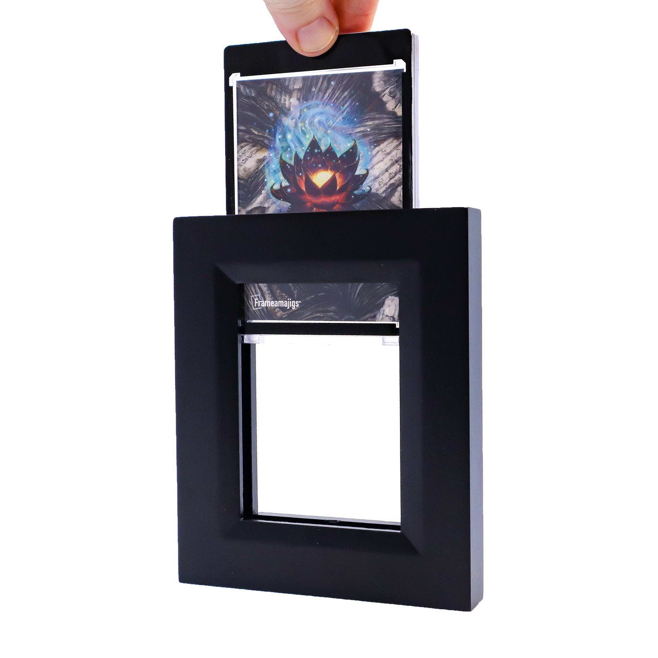 Hand inserts a card featuring a glowing lotus into a black Frameamajigs frame