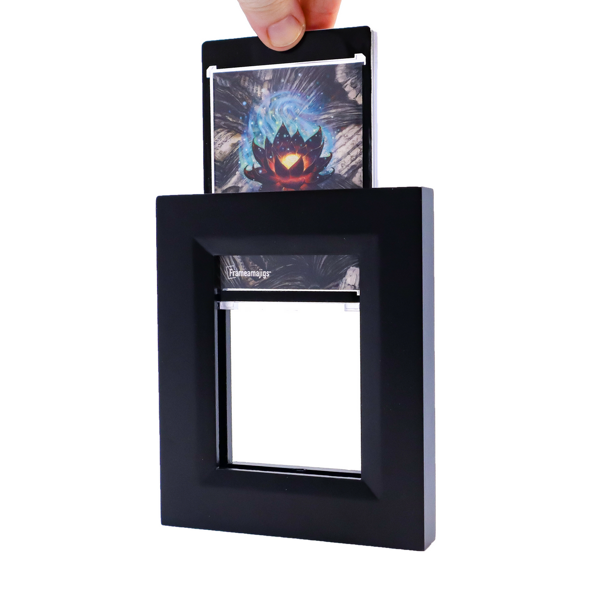 Hand inserts a card featuring a glowing lotus into a black Frameamajigs frame