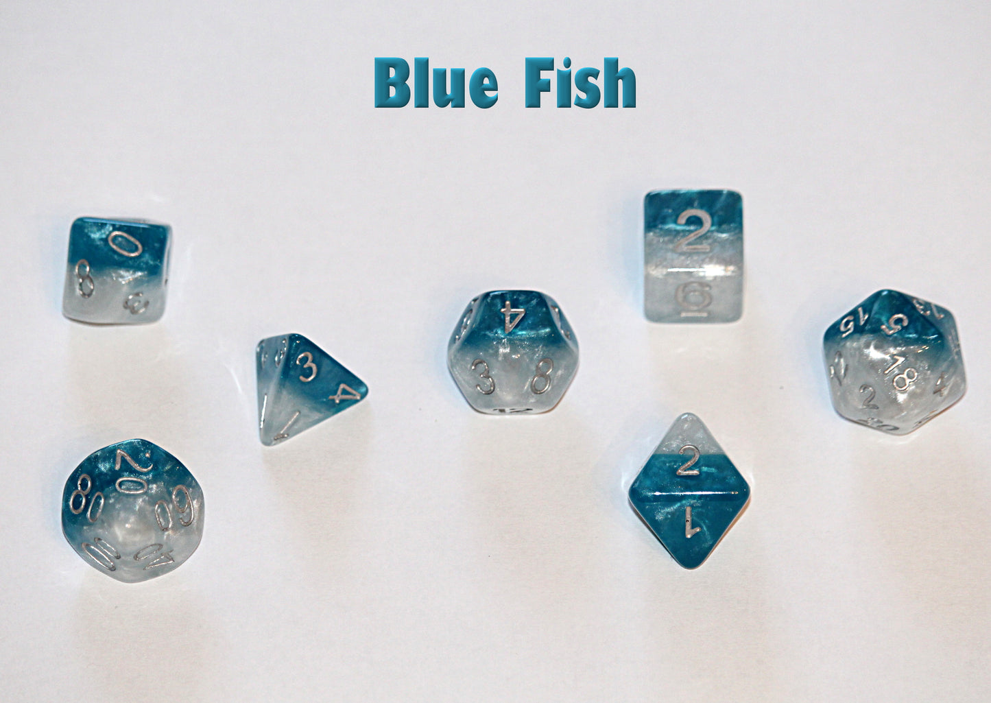 Seven blue and white polyhedral dice with silver numbers, scattered on a white surface. Text "Blue Fish" is above.