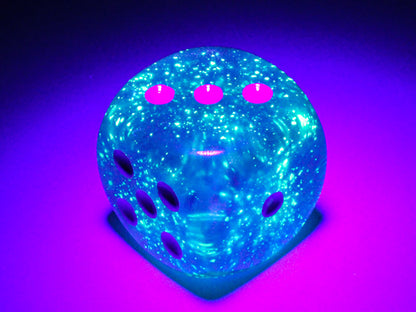 Fluorescent blue-green gaming dice with dark pink pips, glowing under blacklight on a purple surface