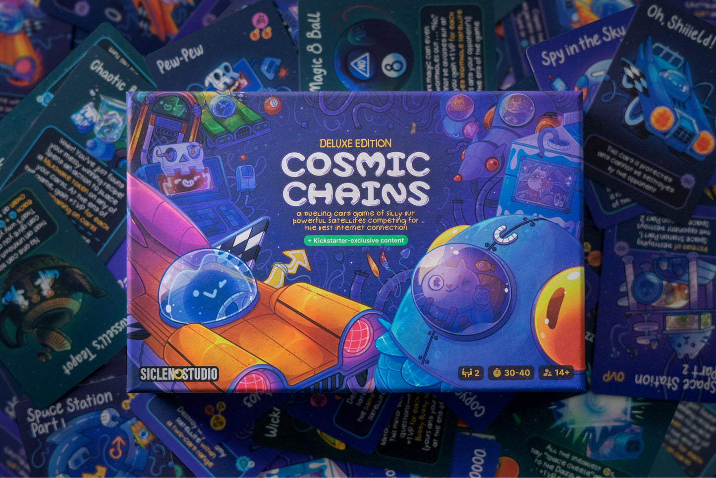 Cosmic Chains Deluxe Edition board game box, featuring cartoon space art, surrounded by colorful game cards