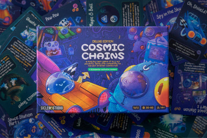 Cosmic Chains Deluxe Edition board game box, featuring cartoon space art, surrounded by colorful game cards
