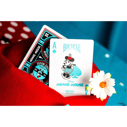 Minnie Mouse Bicycle Ace of Spades playing card, featuring a teal illustration, resting on red fabric next to a daisy
