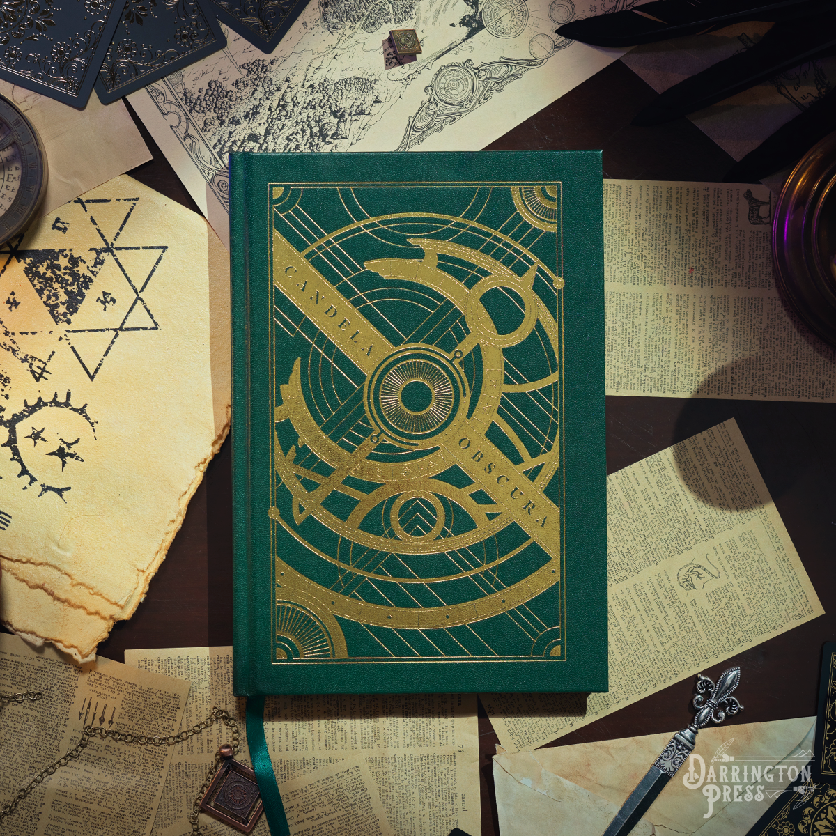 A dark green core rulebook "Candela Obscura" with a gold foil astrolabe design, surrounded by old maps, papers, and a quill
