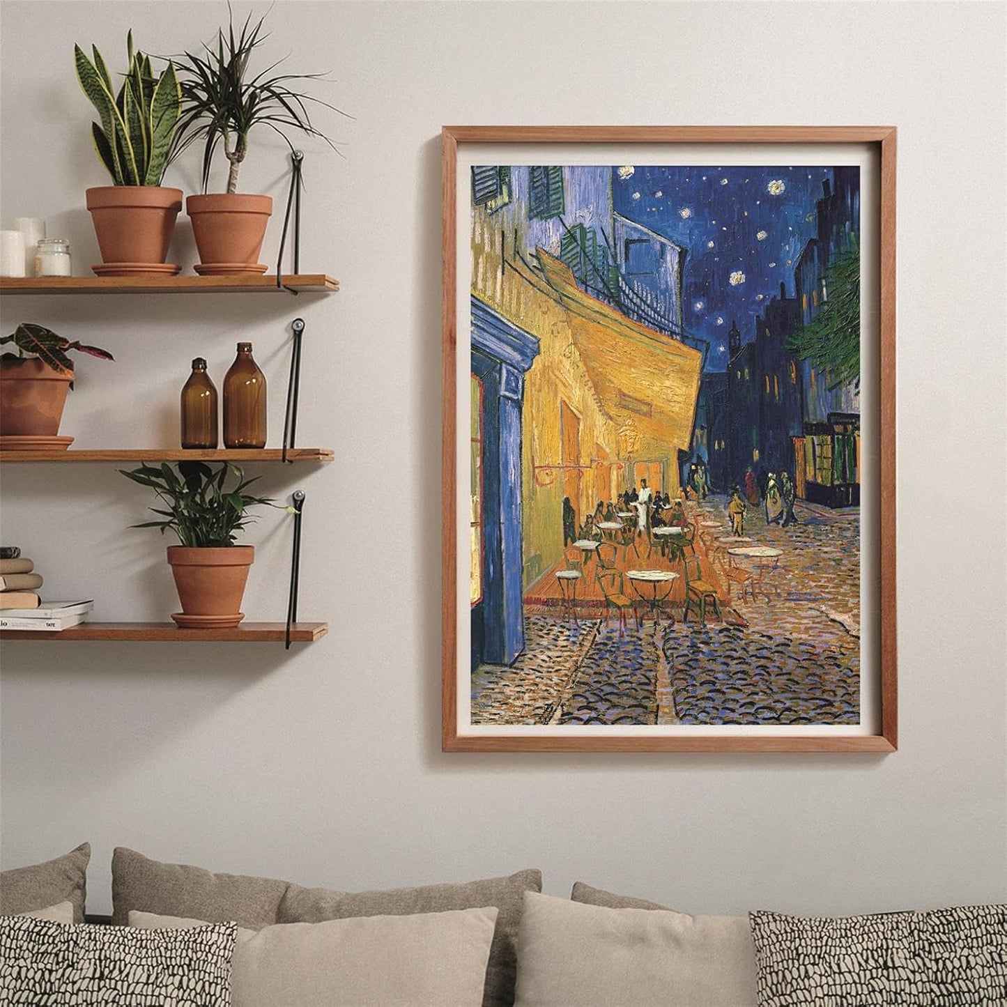 A framed Van Gogh's 'Cafe Terrace at Night' painting, showing an illuminated outdoor cafe under a starry sky, on a wall in a living room
