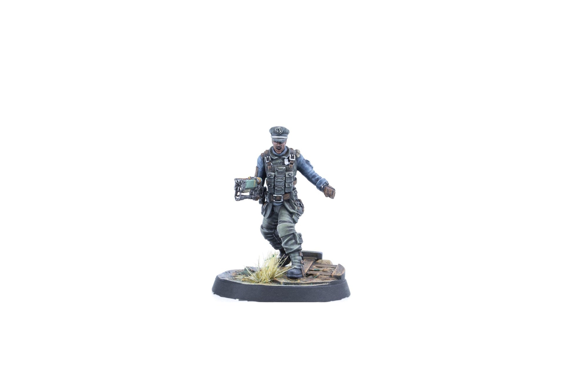 A miniature figure of a man in a grey-blue uniform, tactical vest, and peaked cap, holding a unique green weapon, striding on a base
